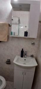 a white bathroom with a sink and a mirror at Apartman Vuk in Budva