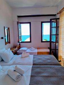a hotel room with three beds and two windows at Hotel Erato in Chorefto