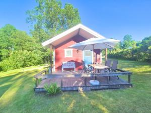 a small red house with a deck with an umbrella at Ferienhaus Stensjö in Holmsjö