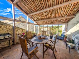 a patio with a table and chairs and a grill at Maison Rives - Village du Livre de Montolieu in Montolieu