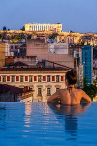 a woman sitting in a infinity pool looking at a city at VISION Omonia Athens in Athens