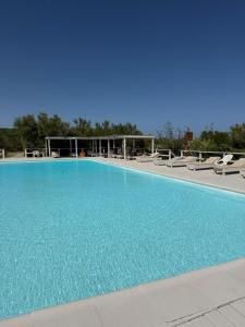 a large blue swimming pool with lounge chairs at Frontera Sur Apart in Miramar