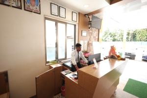 a man sitting at a desk in an office with a computer at Hotel Rangoli Dharampur in Dharampur