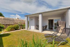 a group of chairs sitting on a patio in a yard at Ferienbungalow Malebisa in Loddin +10 photos