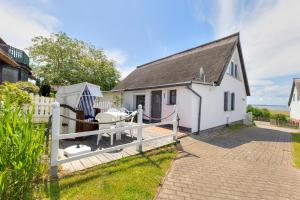 a white house with a white fence and a gate at Ferienhaus Malebisa in Loddin