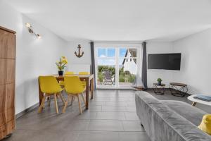 a living room with a couch and a table and yellow chairs at Ferienhaus Malebisa in Loddin