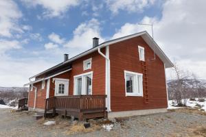 a small house with a porch on a snowy at Jehkas Huoneisto B in Kilpisjärvi