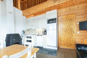 a kitchen with white appliances and a wooden ceiling at Jehkas Huoneisto B in Kilpisjärvi