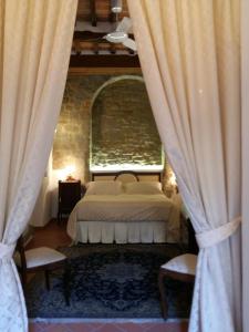 una camera con un letto e due sedie e tende di The Arch a Cortona