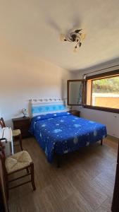 a bedroom with a blue bed and a window at Stazzo gallurese Li Nibbareddhi in Aglientu