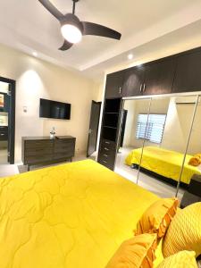 a bedroom with a large yellow bed and a tv at ESEKK Ochi in Ocho Rios