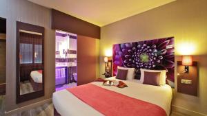 a bedroom with a large bed with a painting on the wall at The Originals City - Hôtel Saint-Martial, Limoges Centre in Limoges