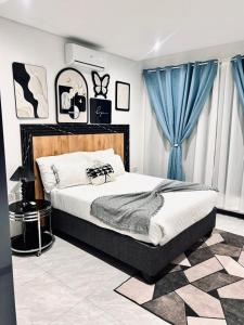 a bedroom with a large bed with blue curtains at Platinum apartments in Gaborone