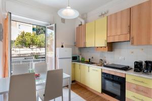 a kitchen with yellow cabinets and a white refrigerator at La Rosa Blu Vacation Home in Sanremo