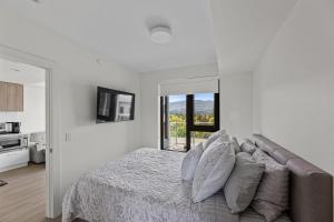a white bedroom with a bed and a large window at Beach Lake Resort in Kelowna +88 photos