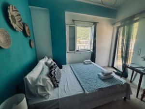 a bedroom with a bed with blue walls and a window at Stay for 2 by Alecos Studios in Poros