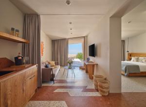 a bedroom with a bed and a living room at Noūs Santorini, a Member of Design Hotels in Mesaria