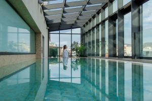 Eine Frau geht in einem Gebäude mit einem Pool in der Unterkunft Graffit Gallery Design Hotel in Warna