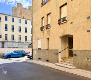 a blue car parked next to a building with a castle at Les 3 Pigeons in Narbonne