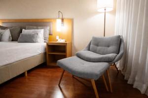 ein Schlafzimmer mit einem Bett und einem Stuhl neben dem Bett in der Unterkunft Intercity Campinas in Campinas