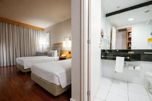 ein Hotelzimmer mit zwei Betten und einem Badezimmer in der Unterkunft Intercity Campinas in Campinas