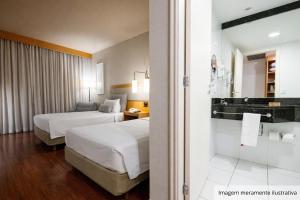 ein Hotelzimmer mit zwei Betten und einem Badezimmer in der Unterkunft Intercity Campinas in Campinas