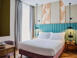 ein Schlafzimmer mit einem großen weißen Bett mit blauem Kopfteil in der Unterkunft Hotel Giacomo Morra Alba - Handwritten Collection in Alba