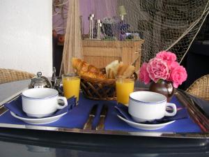 a tray with two cups and a basket of bread and orange juice at LA VILLA DU CAP in Cap-Ferret