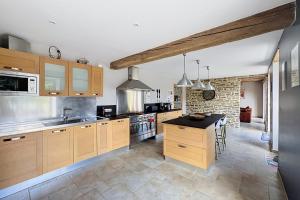 a large kitchen with wooden cabinets and a kitchen island at Maisons de Familles Quiet family-friendly vacation rental with a spa in Équilly