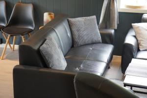 a leather couch in a room with chairs at Panorama Valley Lofoten in Bøstad