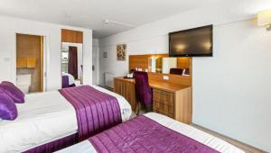 a hotel room with two beds and a desk at Sandy Lodge Hotel Newquay in Newquay