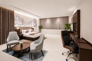 a hotel room with a bed and a desk and chairs at Lotus Vista Hotel in Alwar +40 photos