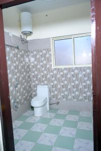 a bathroom with a toilet and a window at Hotel King By Panch Aarohan in Pithorāgarh