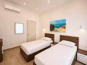 two beds in a room with white walls at Il-Kenn ta Roża Maisonette in Qala