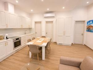 a kitchen with white cabinets and a table and chairs at Il-Kenn ta Roża Maisonette in Qala +9 photos