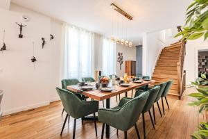 a dining room with a wooden table and green chairs at La Maison Opaline in Reims
