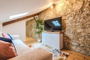 a living room with a stone wall with a flat screen tv at La Maison Opaline in Reims