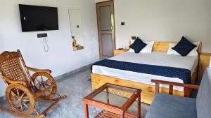 a bedroom with a bed and a chair and a tv at Ganga Nature Nest in Hawālbāgh