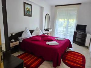 a bedroom with a large bed with a red blanket at Club Onix Apartments in Neptun