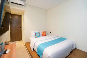 a bedroom with a large white bed with colorful pillows at SANS Stay Arkana Seturan Pakuwon Mall in Yogyakarta