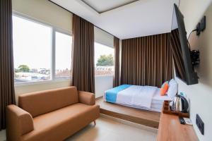 a hotel room with a bed and a couch at SANS Stay Arkana Seturan Pakuwon Mall in Yogyakarta