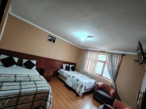 a bedroom with two beds and a chair and a window at Hostal el barranco in Cuenca