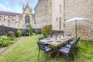 a table with chairs and an umbrella in a yard at La Maison Opaline in Reims