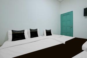 a white bed with black and white pillows and a green door at Collection O Near Taiping Mall Formerly Axis Hotel in Taiping
