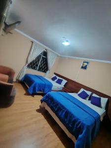 two beds in a room with blue sheets at Hostal el barranco in Cuenca