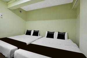 two beds in a room with white walls and black pillows at Collection O Near Taiping Mall Formerly Axis Hotel in Taiping