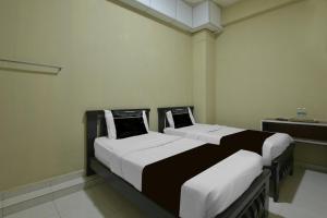 two beds in a room with white and black at Collection O Near Taiping Mall Formerly Axis Hotel in Taiping
