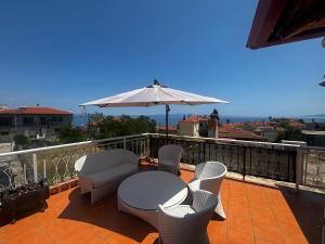 a balcony with a table and chairs and an umbrella at Nefeli's cozy apartment afytos in Afitos