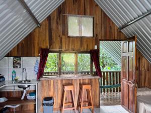 a kitchen with wooden walls and a counter with stools at Cabaña Escondida Rio Celeste in El pilon