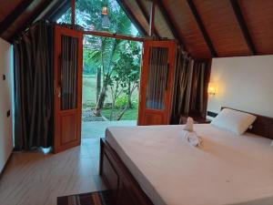 a bedroom with a bed and a large window at Sunset Dream Cabana in Tangalle